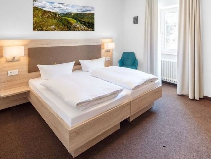 Bild von einem Hotelzimmer mit hellem Holz und hellen Vorhängen