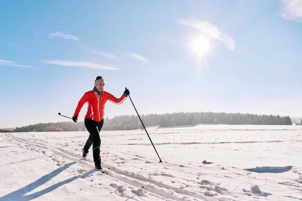Bild von einer Langläuferin im klassischen Fahrstil auf einspuriger Loipe bei blauem Himmel und viel Schnee