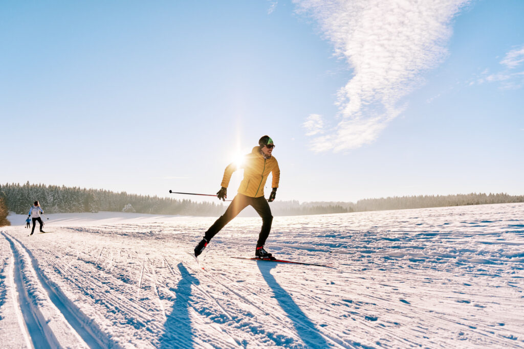 Picture of cross-country skiers on the skating track with blue sky and lots of snow