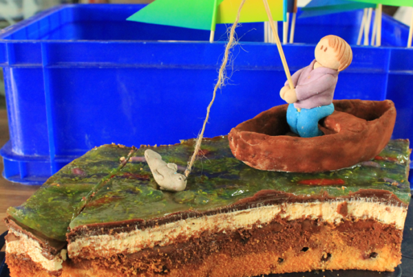 Bild von einem Stück Donauwelle mit modelliertem Boot mit Insasse, der einen Fisch an der Angel hat vor einer blauen Kunststoffkiste