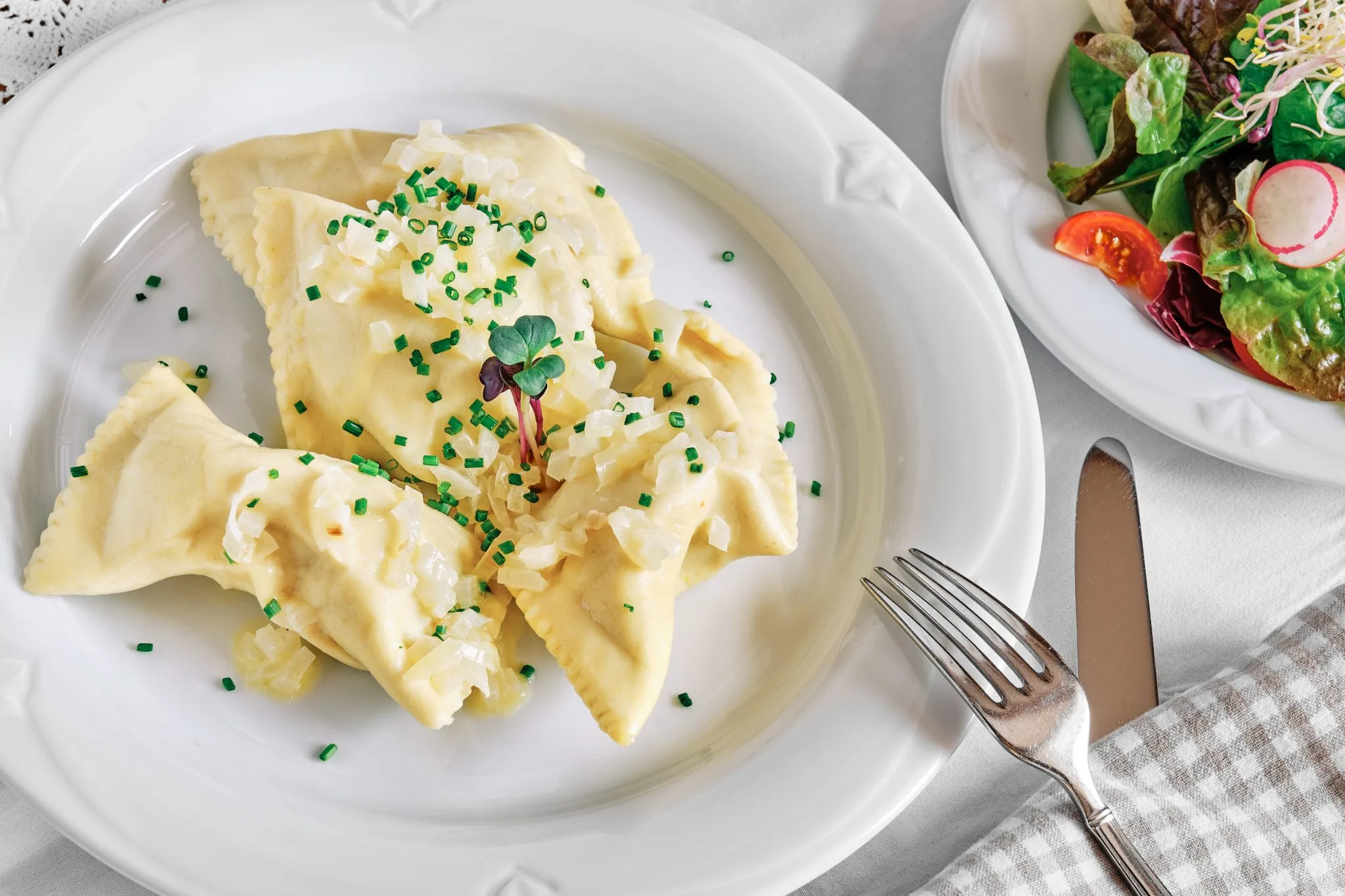 Bild von Maultaschen mit Zwiebeln auf Teller und Salat