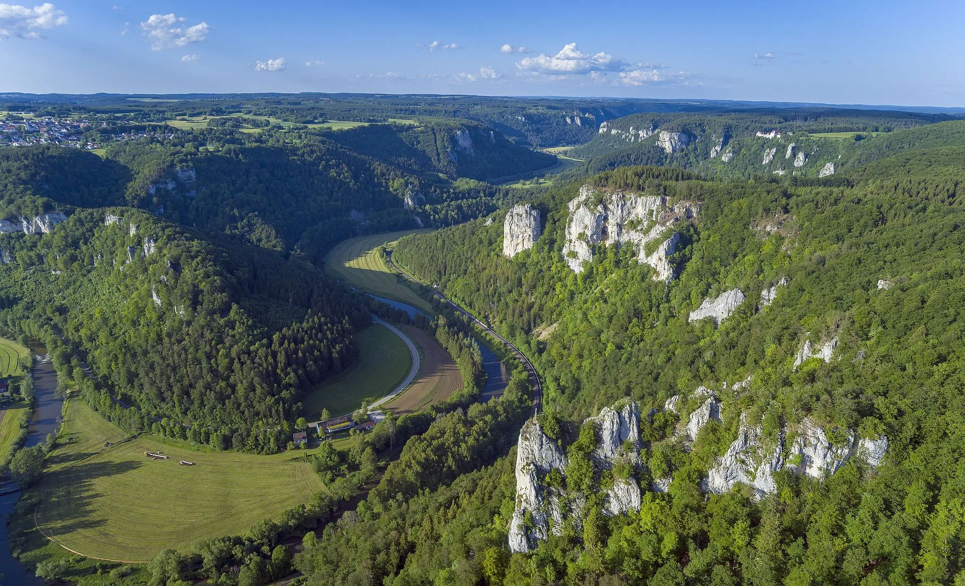 Luftbild über ein felsiges und bewaldetes Tal durch das sich die Donau schlängelt