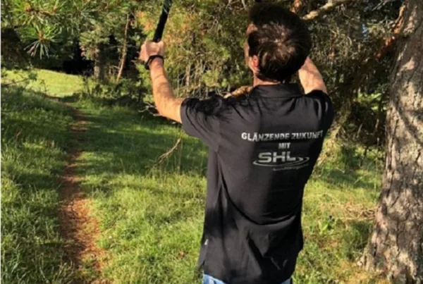 Ein Mann schneidet einen herabhängenden Ast am Wanderweg