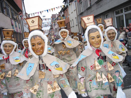 Maskierte Fastnachtsnarren in Mühlheim mit Mühlentrog auf dem Kopf
