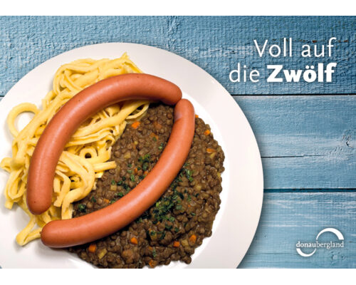 Donaubergland Postkartenmotiv mit Teller auf dem Linsen, Spätzle und ein Paar Saitenwürste sind.